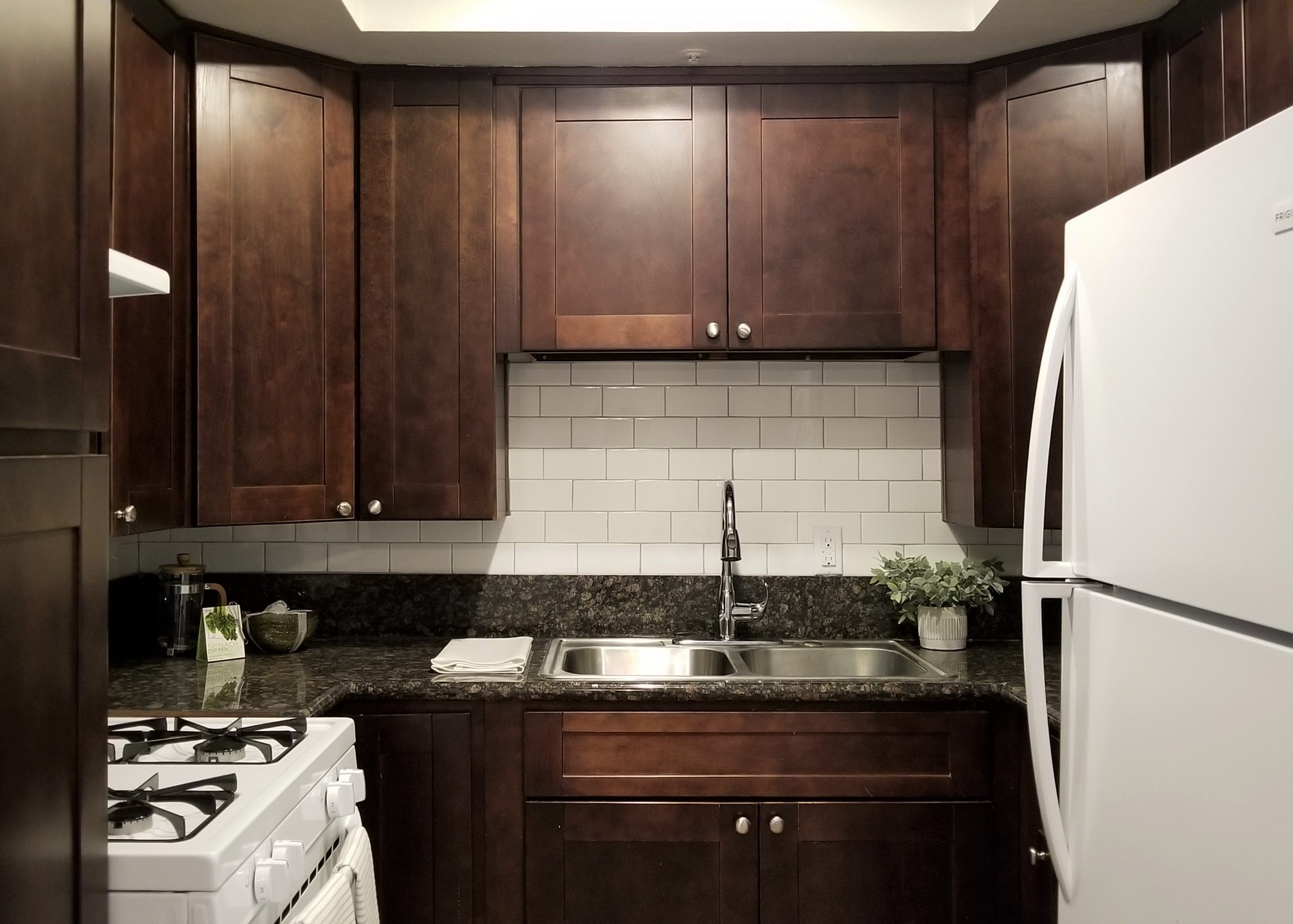 Kitchen cabinetry, stove, granite counter top, and refrigerator